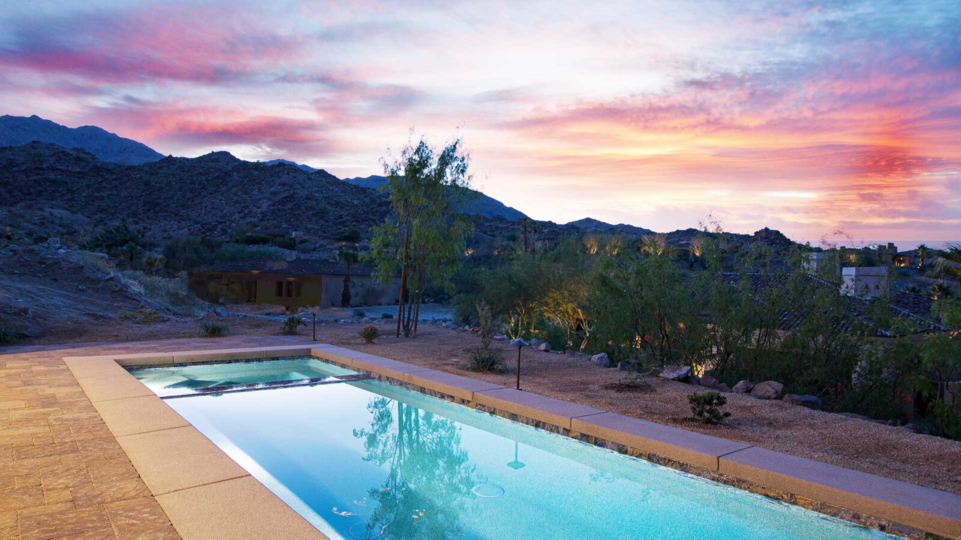 dusk beside pool with mountain backdrip and red colored sunset.